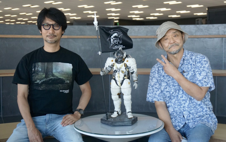 Хидео Кодзима (слева) и&amp;nbsp;Мамору Осии (справа). Между ними стоит Люденс — маскот и герой логотипа&amp;nbsp;Kojima Productions.