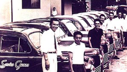 Ричард Стюарт вместе со&amp;nbsp;своими сотрудниками на&amp;nbsp;фоне штаб-квартиры Service Games Japan, 1957&amp;nbsp;год.